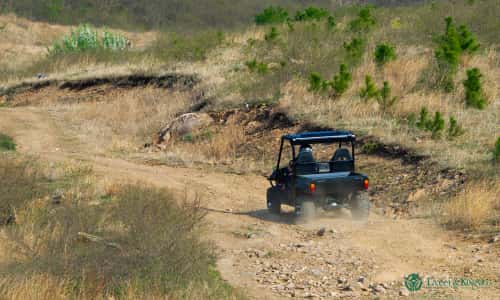 An electric UTV speeding across mountainous terrain.